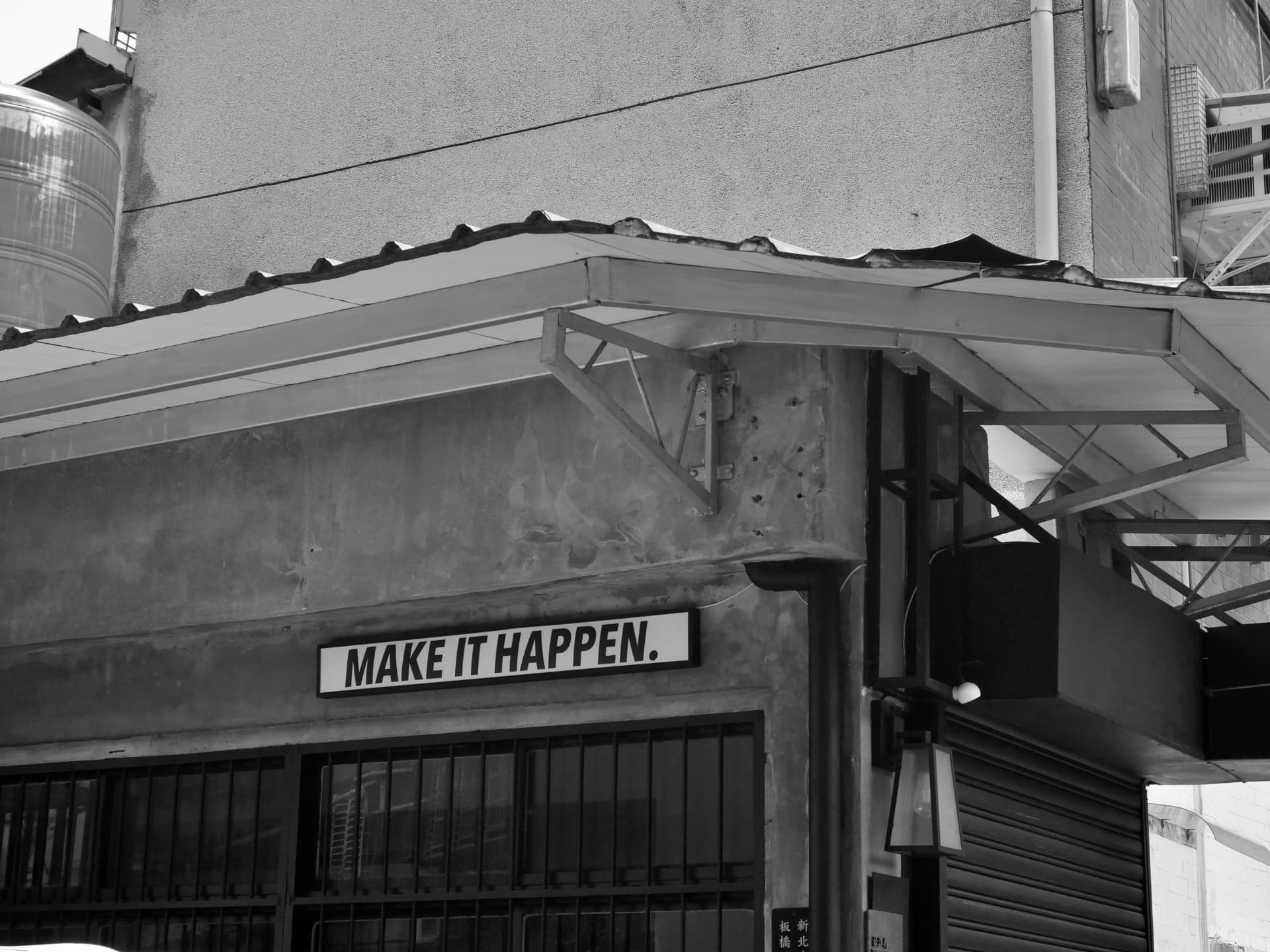 A weathered concrete wall bearing a sign that reads 'Make it happen.'